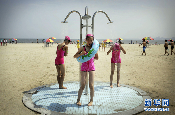 　　当地时间7月29日，朝鲜元山，参加松涛园国际少年团夏令营的朝鲜女孩穿着款式相似的泳衣在沙滩上冲凉。（图片来源：东方IC）